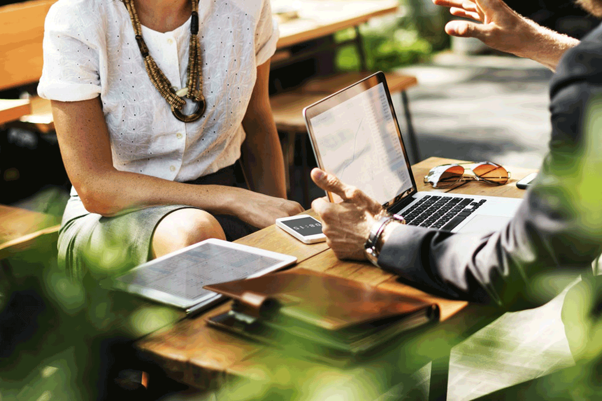 A couple engrossed in work, sitting at a table, using a laptop to collaborate and accomplish tasks efficiently.