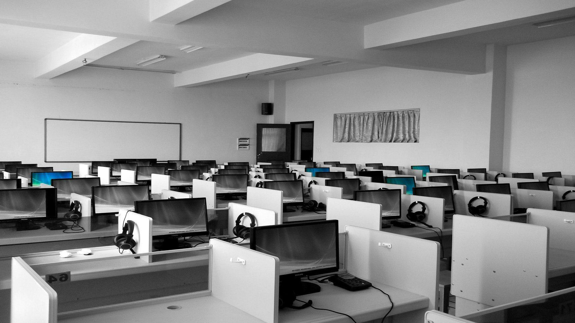 a room of office with computers and headphones and a white board