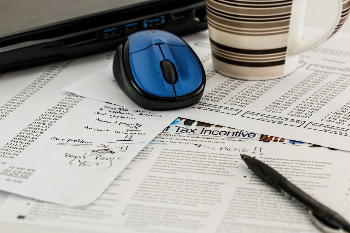 a computer mouse with a pen and coffee cup on a papers