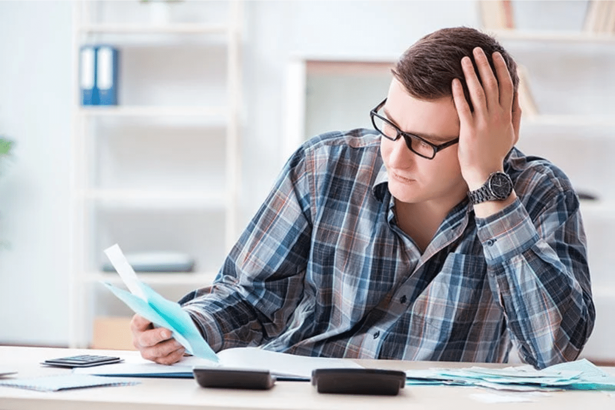 A person holding his head looking at papers