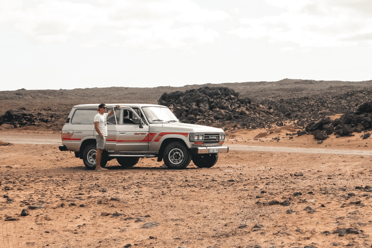 a person standing next to a car in desert