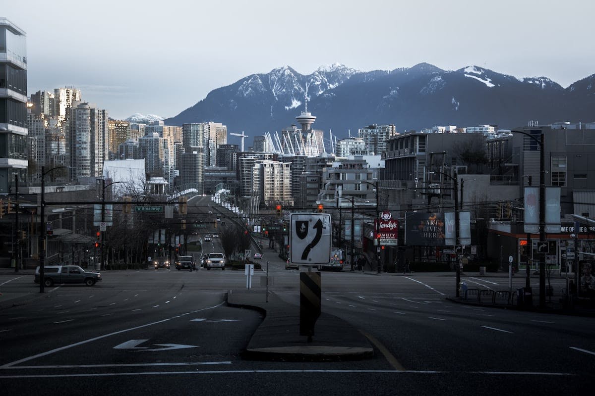 A city street with a stop sign and majestic mountains in the background, creating a picturesque urban landscape.