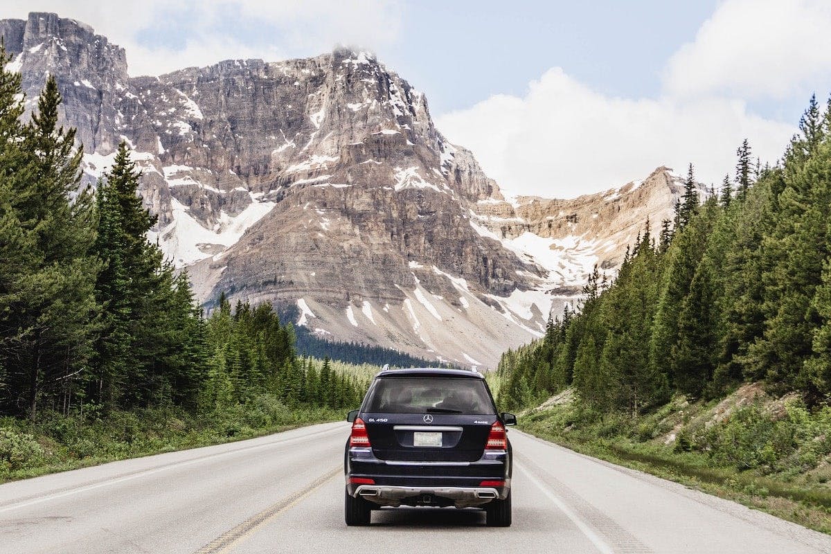 a car on a road with mountains in the background