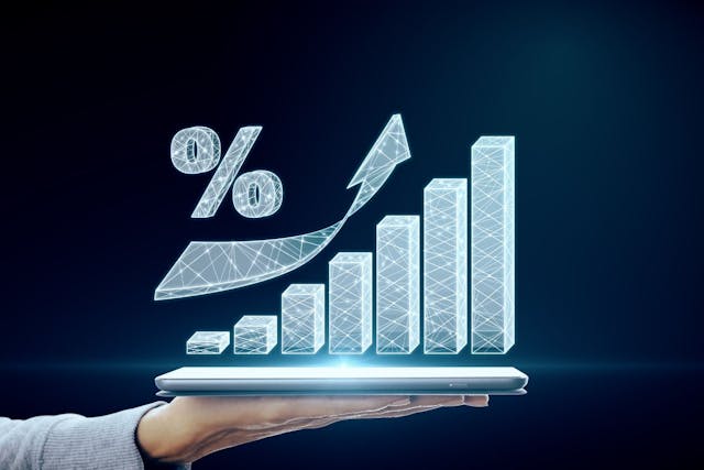 A hand holding a smartphone that is projecting a graph showing positive portfolio growth