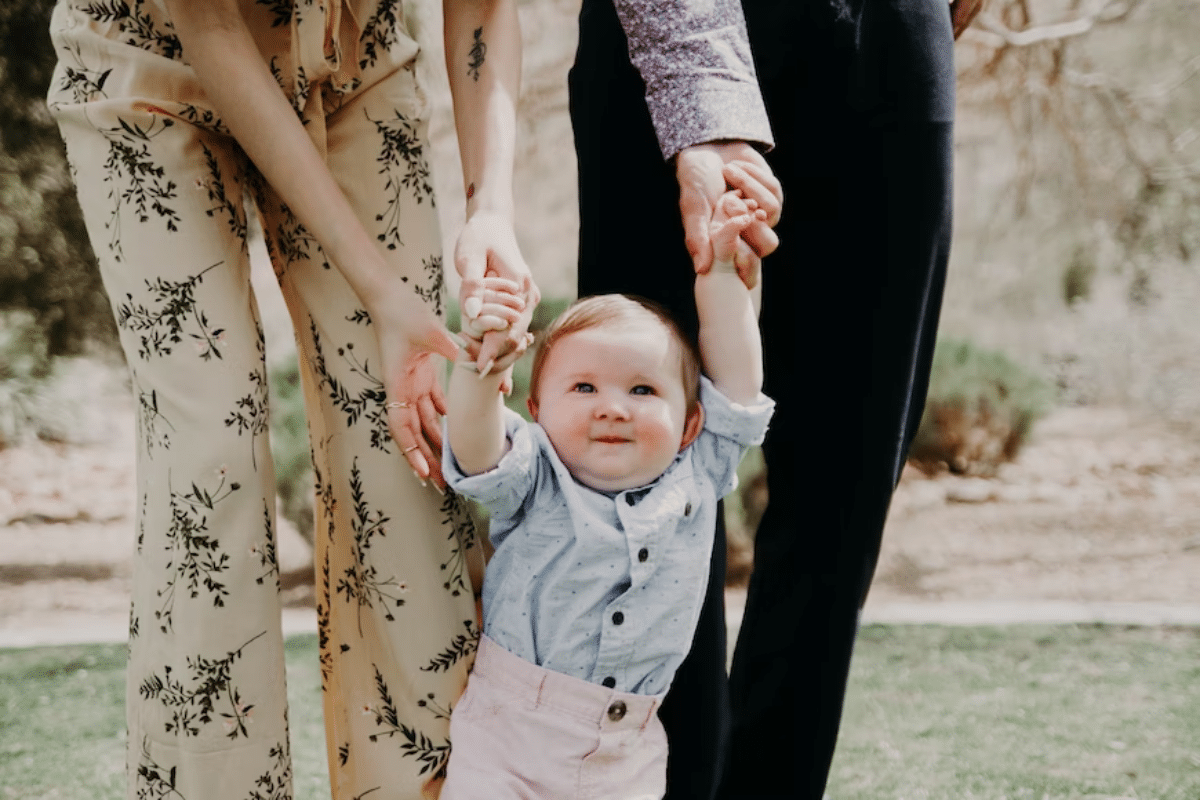 a baby holding hands with a baby standing next to a person and a person