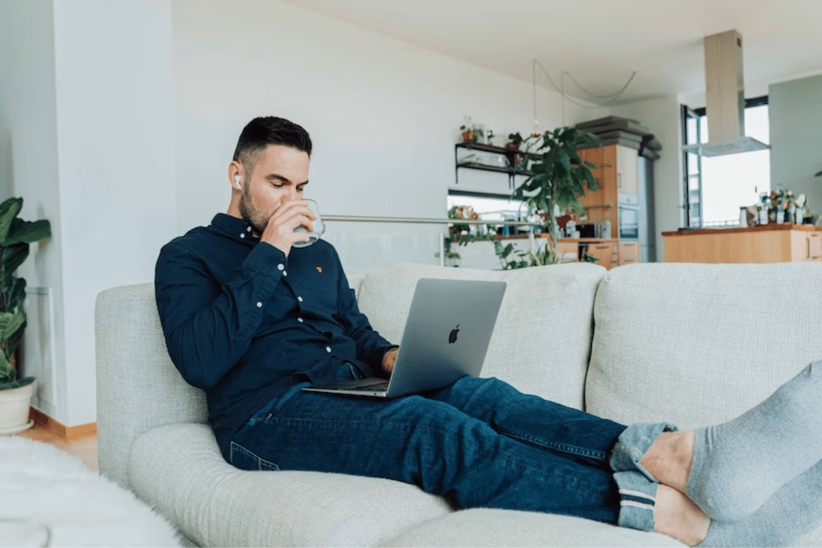 a person sitting on a couch drinking from a glass