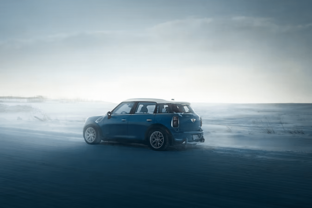 a blue car driving on a snowy road