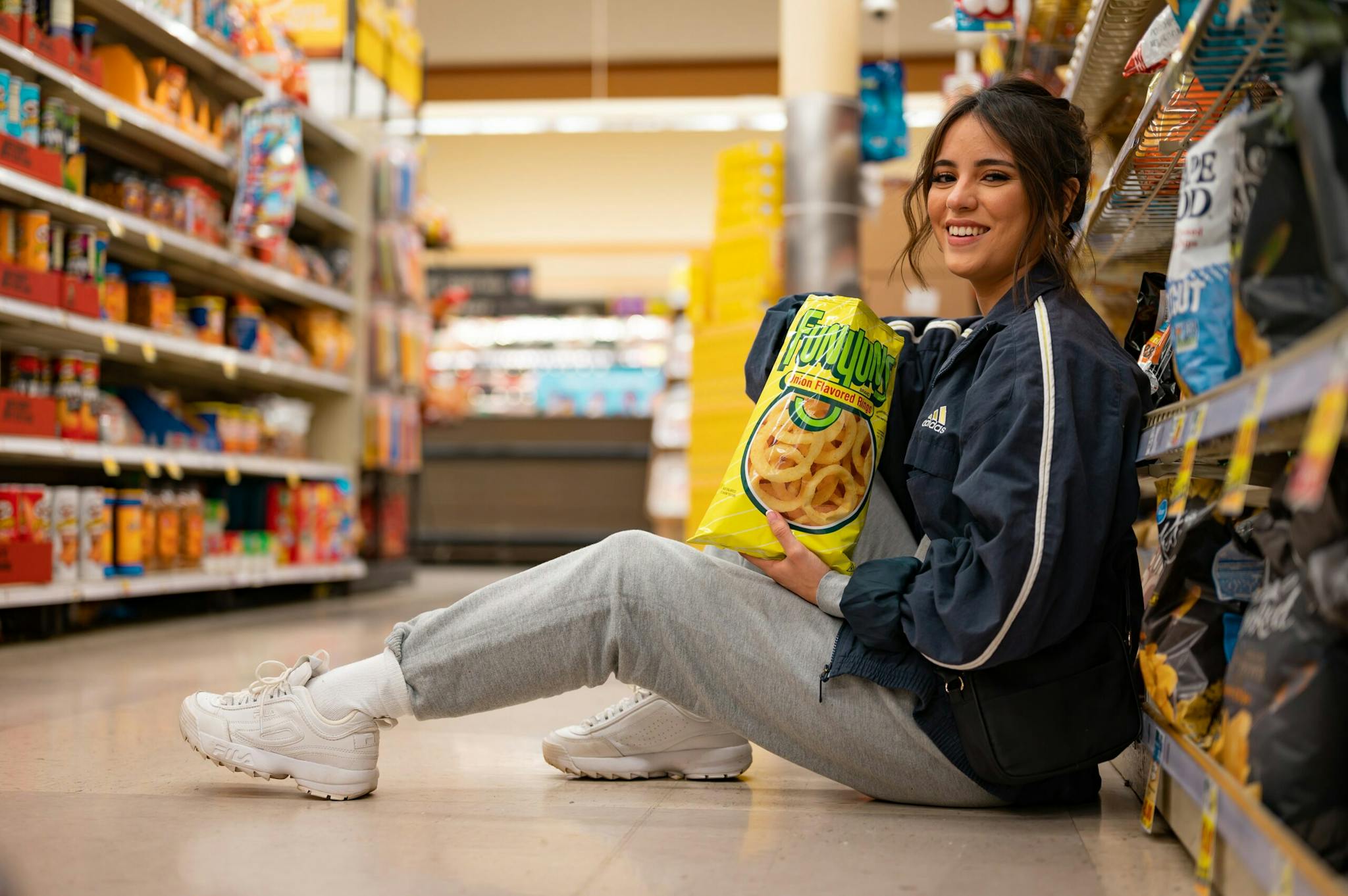 A girl is in the supermarket with a Kroger shopper in hand.