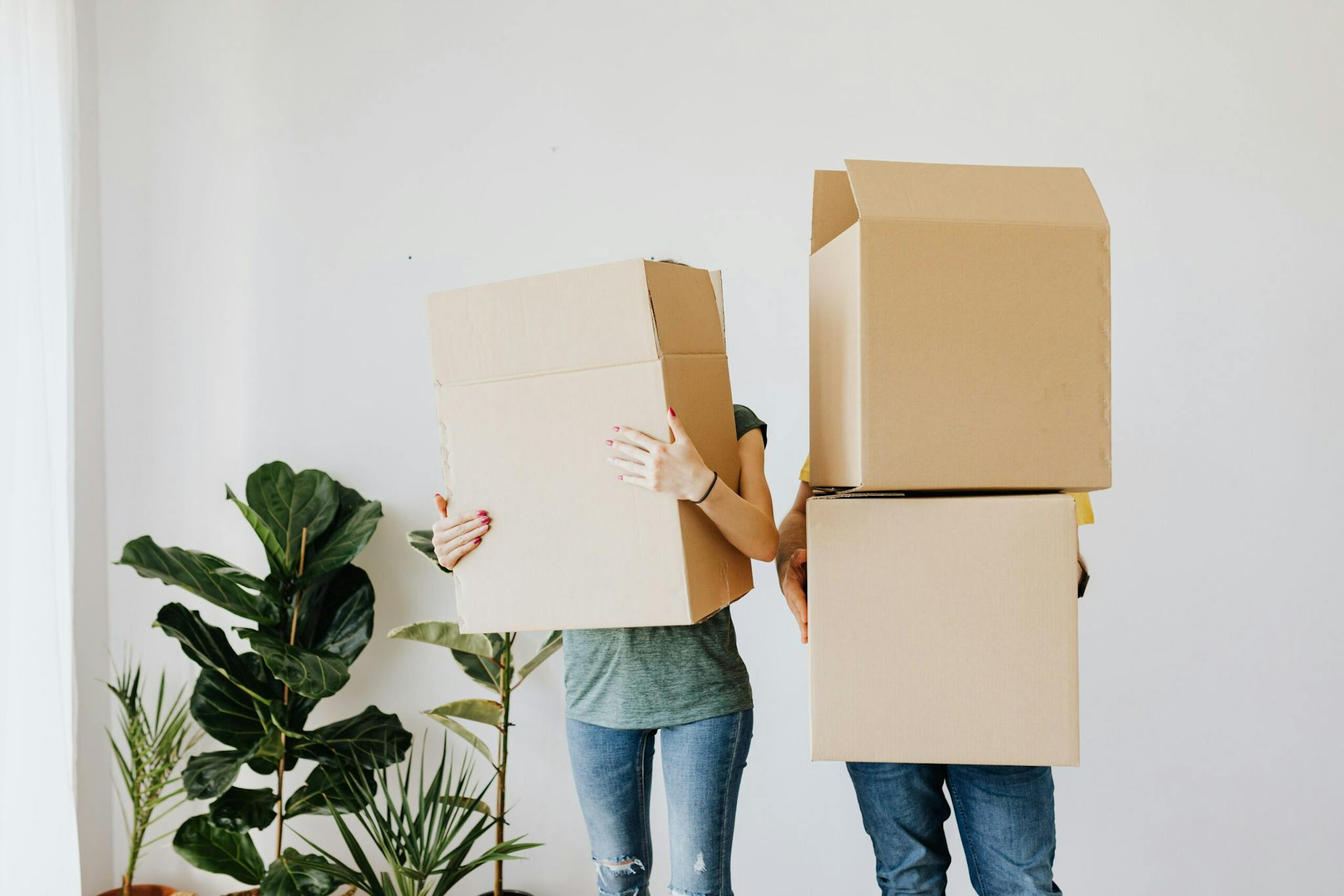 Two individuals holding boxes in an empty room, preparing for relocation or storage