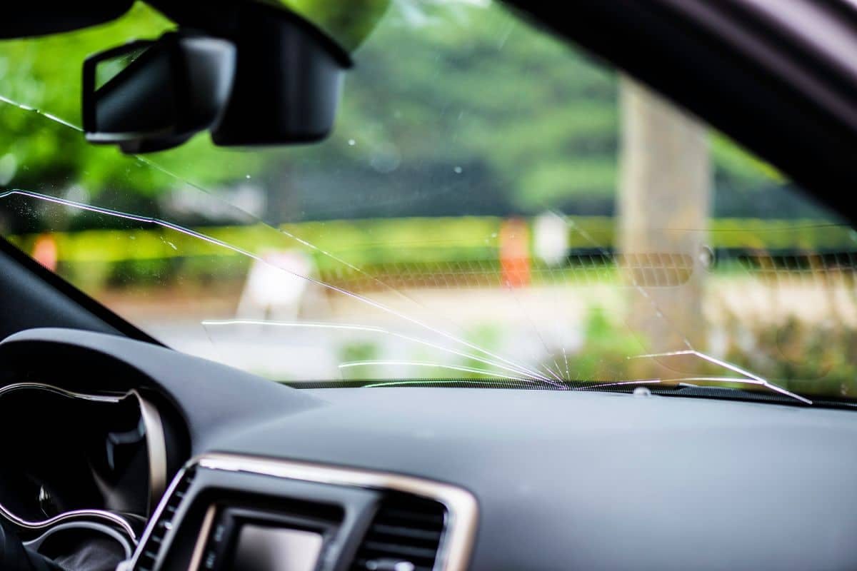 A damaged car windshield and broken window are visible in the image, indicating significant vehicular damage