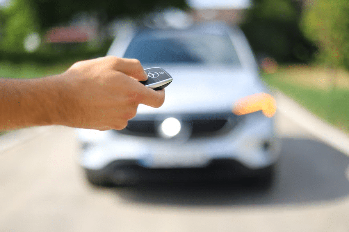 a hand holding a remote control to a car