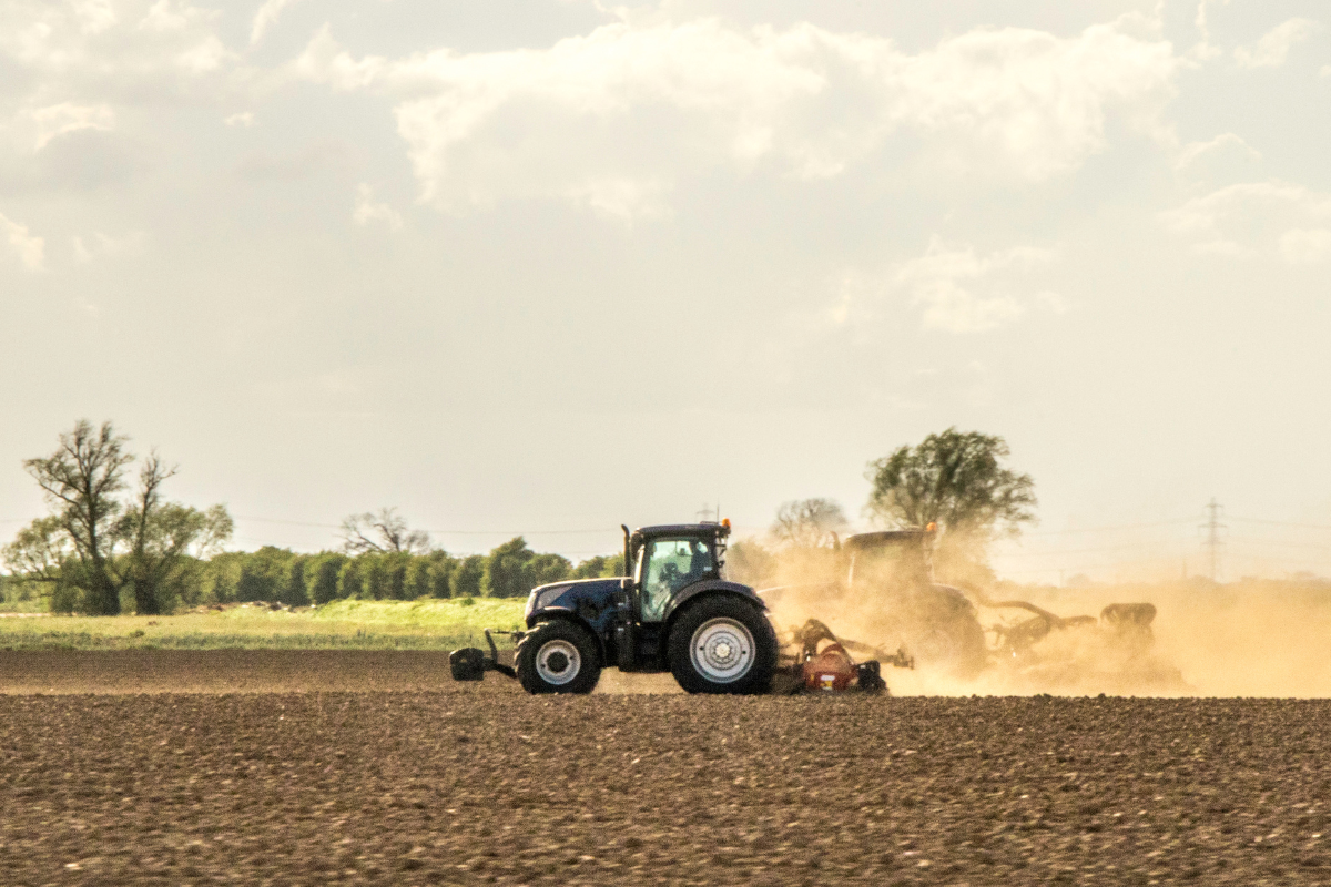 Farming tractor plowing field with plow, prepping land for planting season