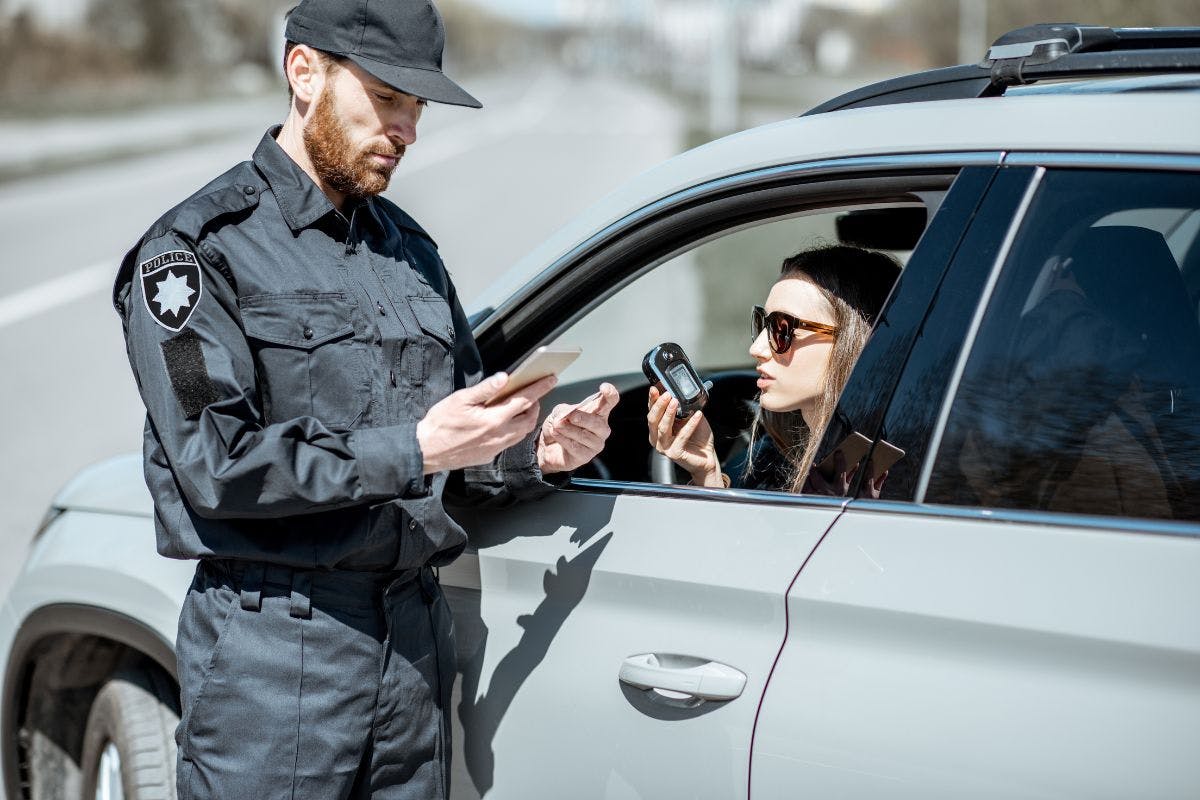 a police officer in uniform checking license of a girl in a car