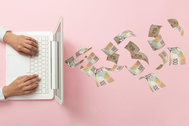 woman's hands on a white laptop that is dispensing cash